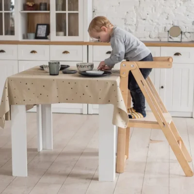 Kind zit op Montessori leertoren aan keukentafel, bezig met een activiteit